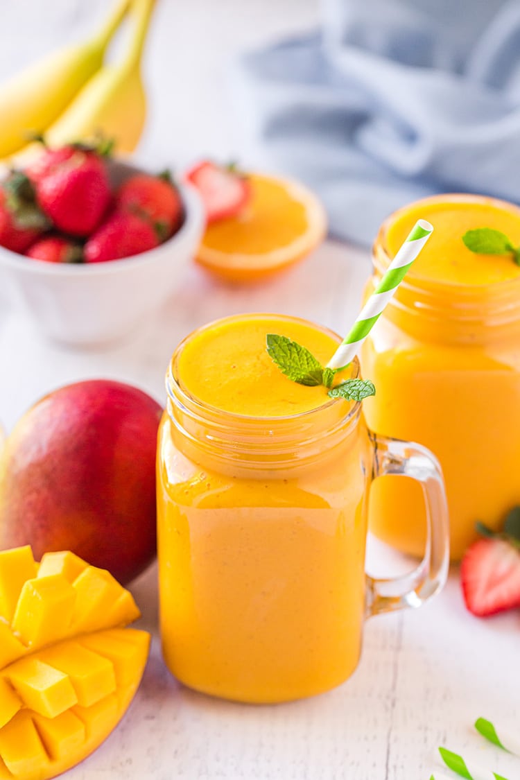 Mango smoothies in glasses with mint sprig and striped straws