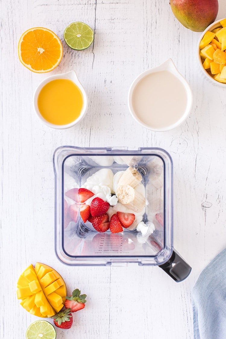 Strawberries, banana, and yogurt mango smoothie ingredients in blender