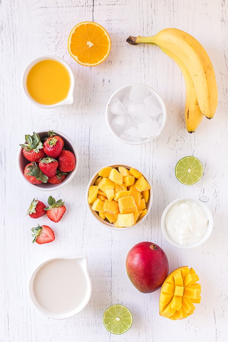 Ingredients for mango smoothie recipe on white washed wood background