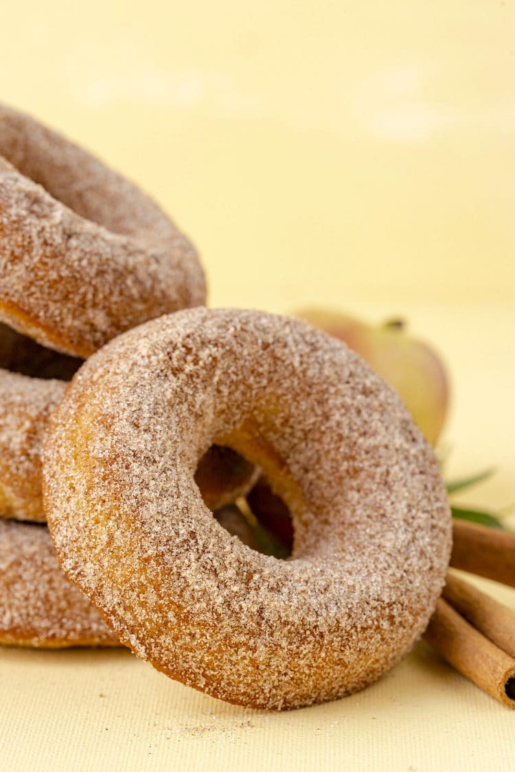Close up of cinnamon sugar apple cider donut on yellow background