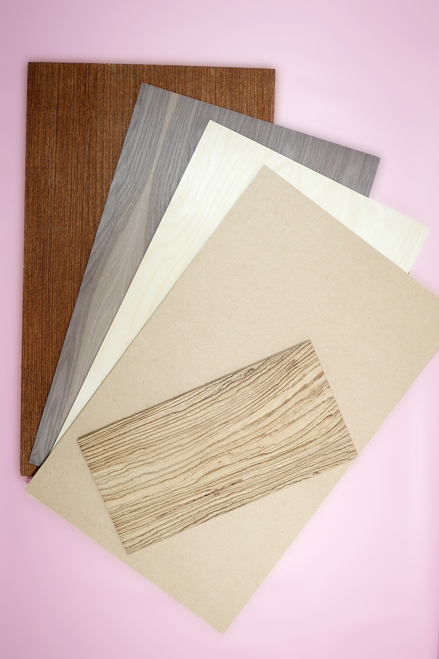 Five different types of wood sheets on a pink background