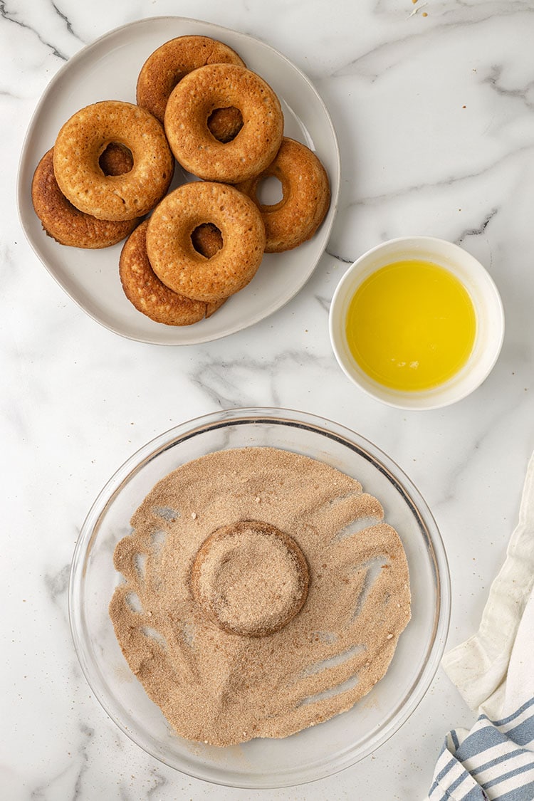 covering the donuts with cinnamon and sugar in bowl