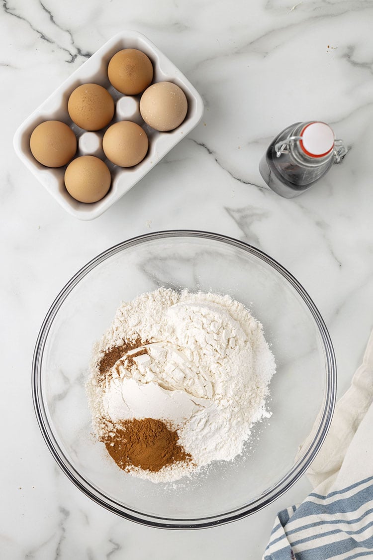 Clear glass bowl of unmixed dry ingredients on a grey marble background