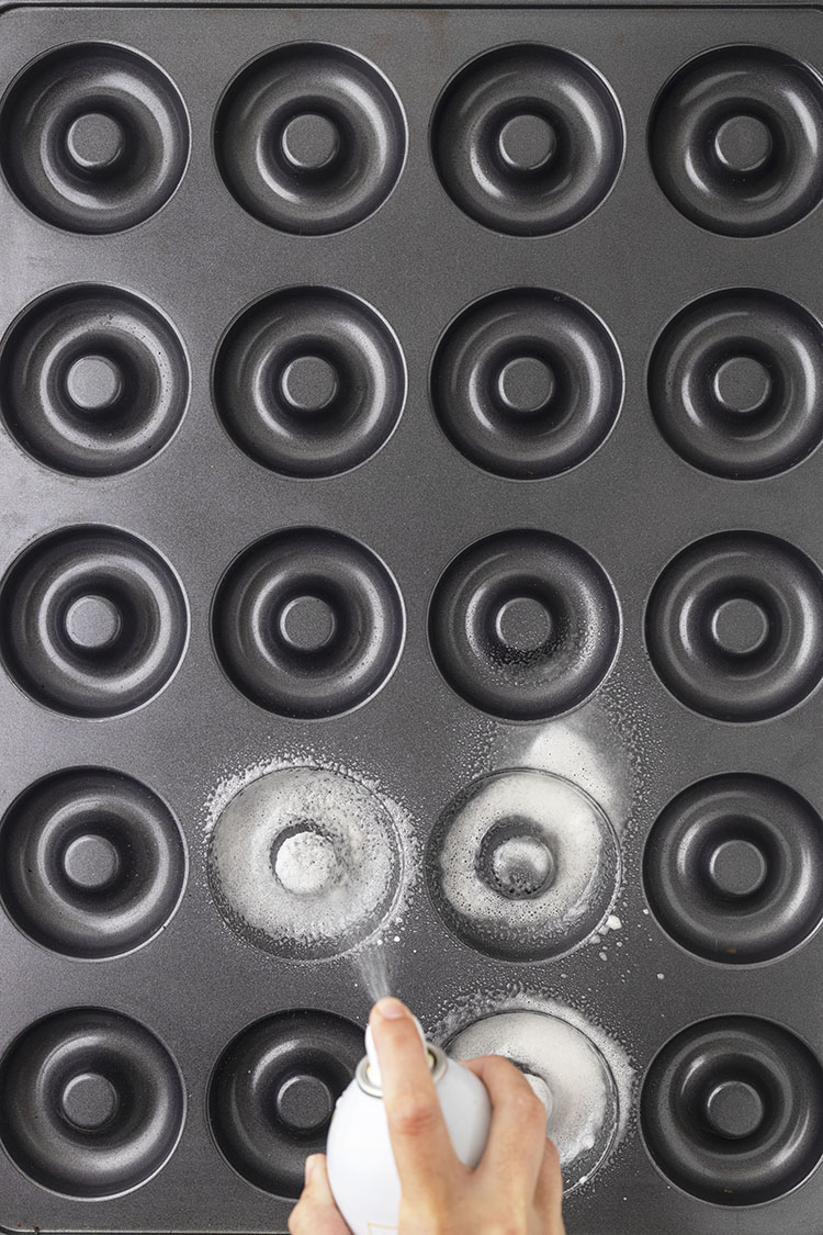 spraying baking pan for apple cider donuts