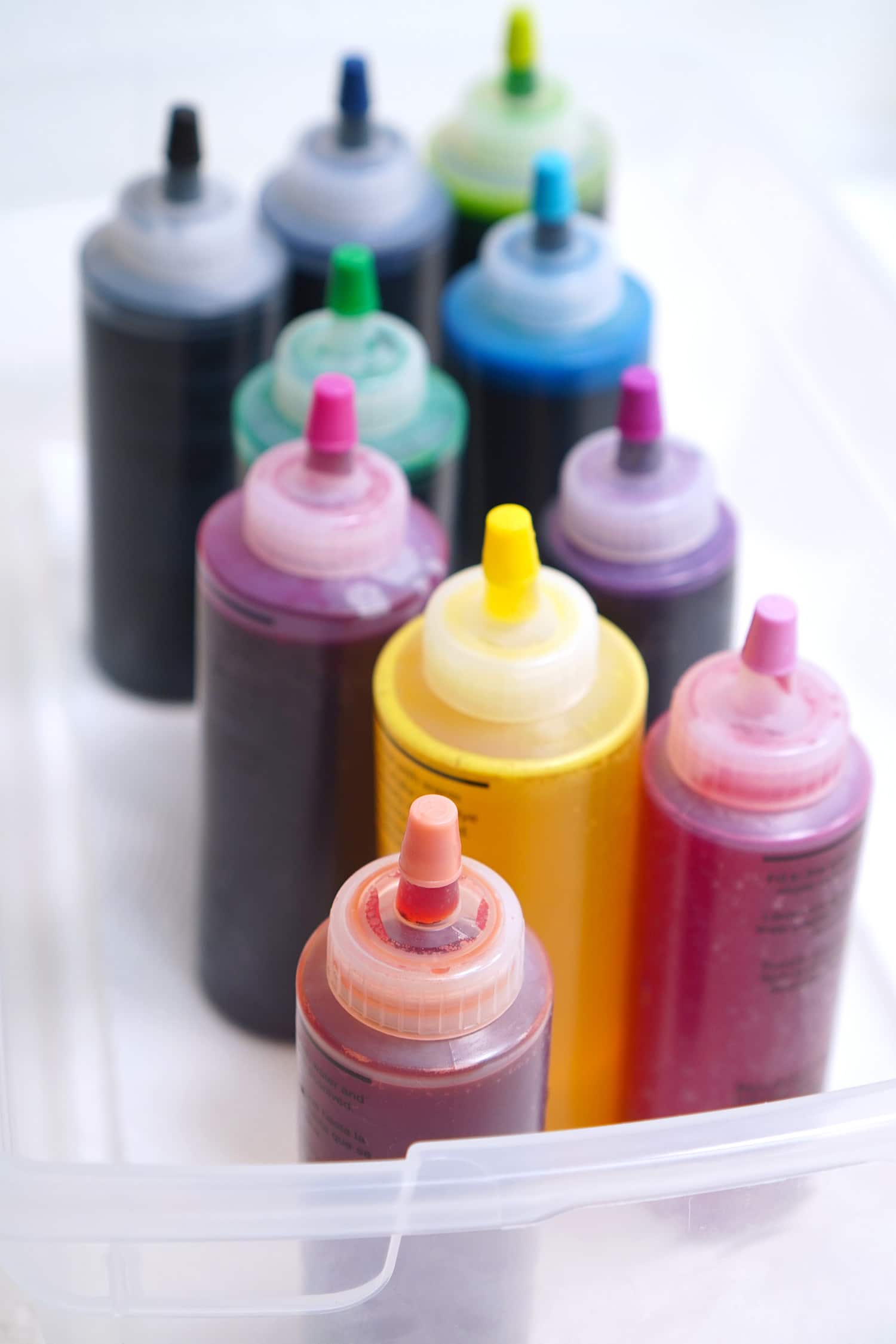 Colorful squeeze bottles of liquid tie-dye on a white background