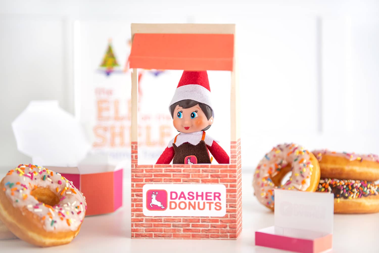 Elf on the Shelf with mini donut box, full sized sprinkle donuts, and donut shop apron prop