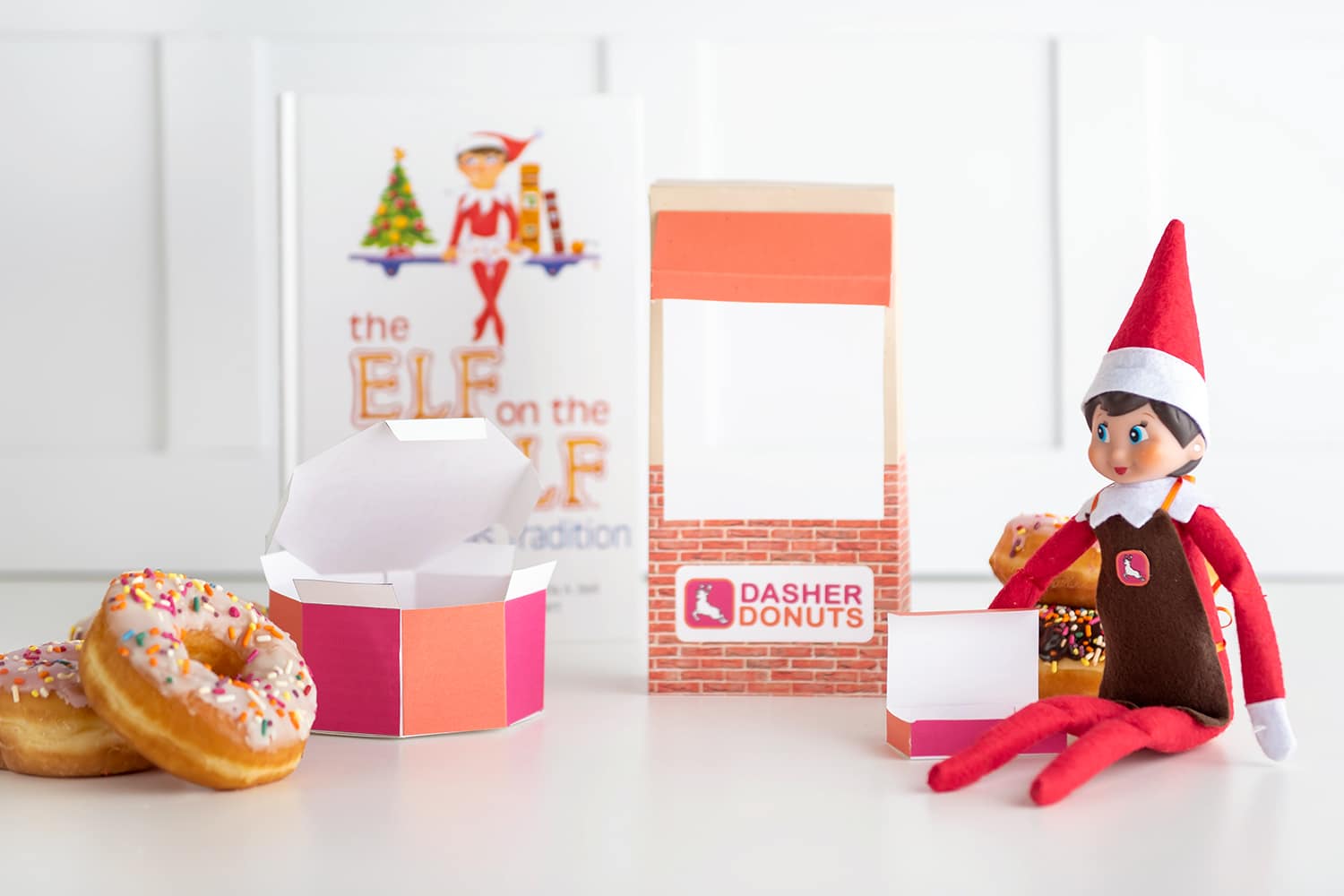 Elf on the Shelf with mini donuts, full sized donuts and box, and donut shop apron prop