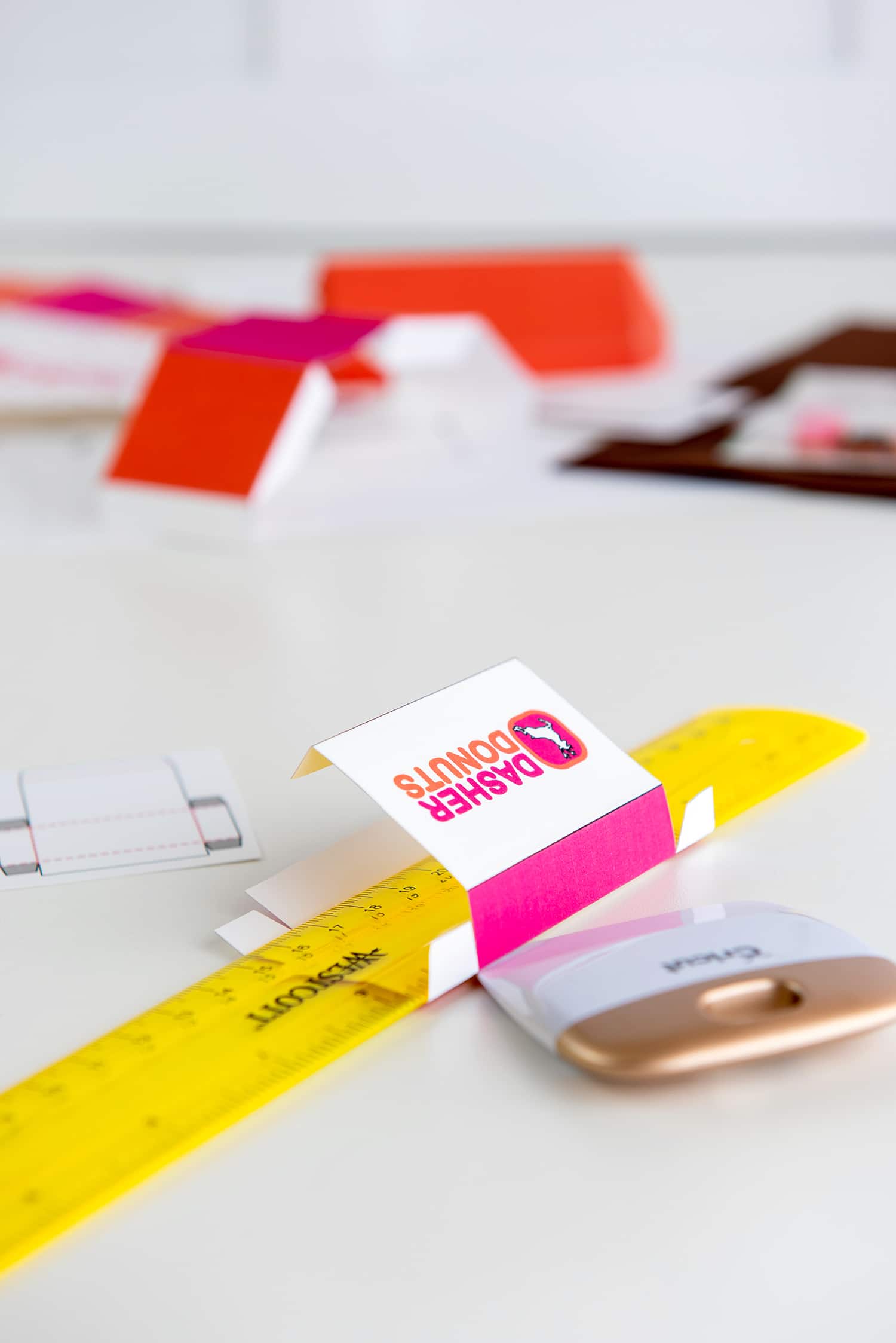 Using a bright yellow ruler to fold a printable mini donut box template for Elf on the Shelf