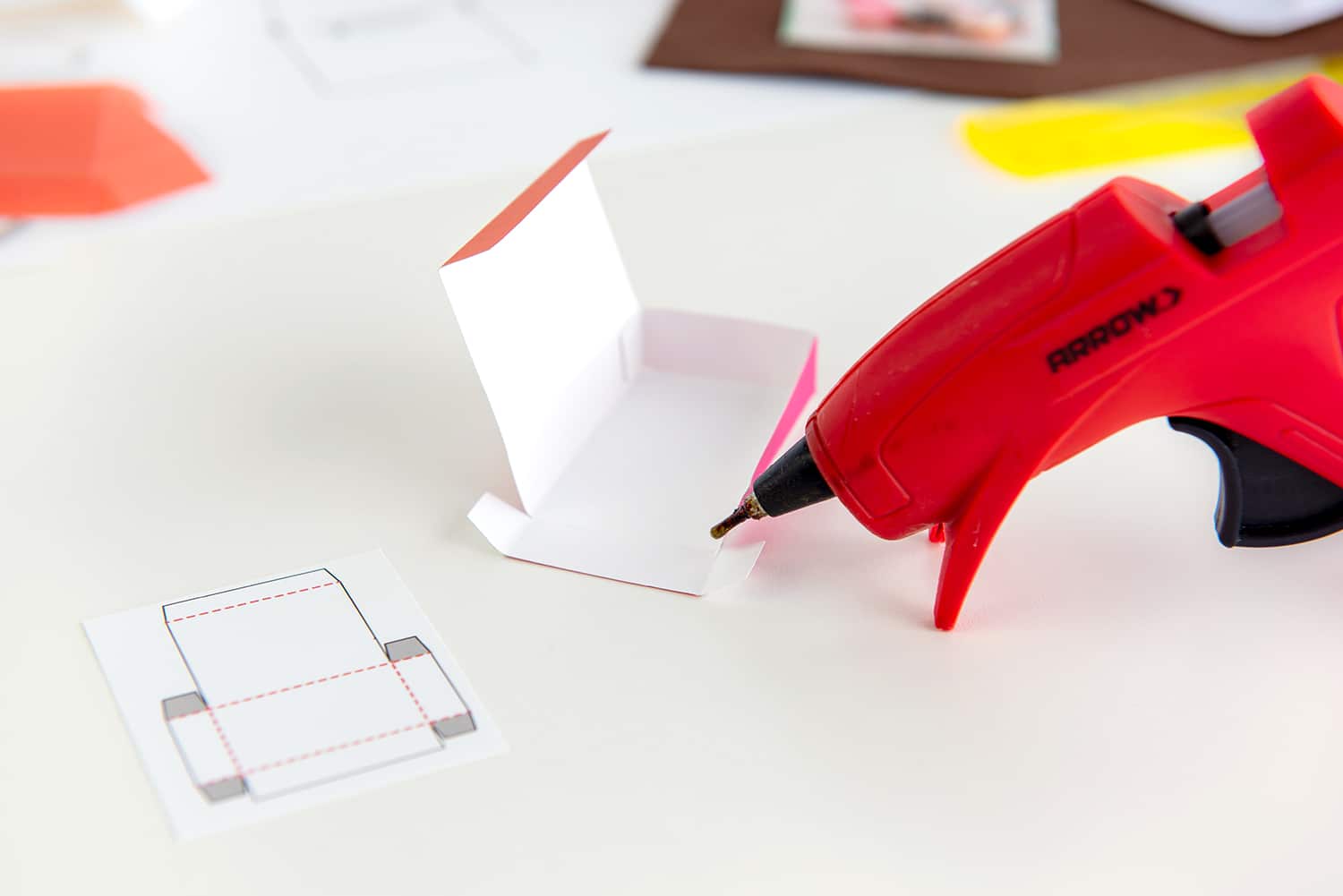 Hot glue gun gluing a mini donut box with folding template