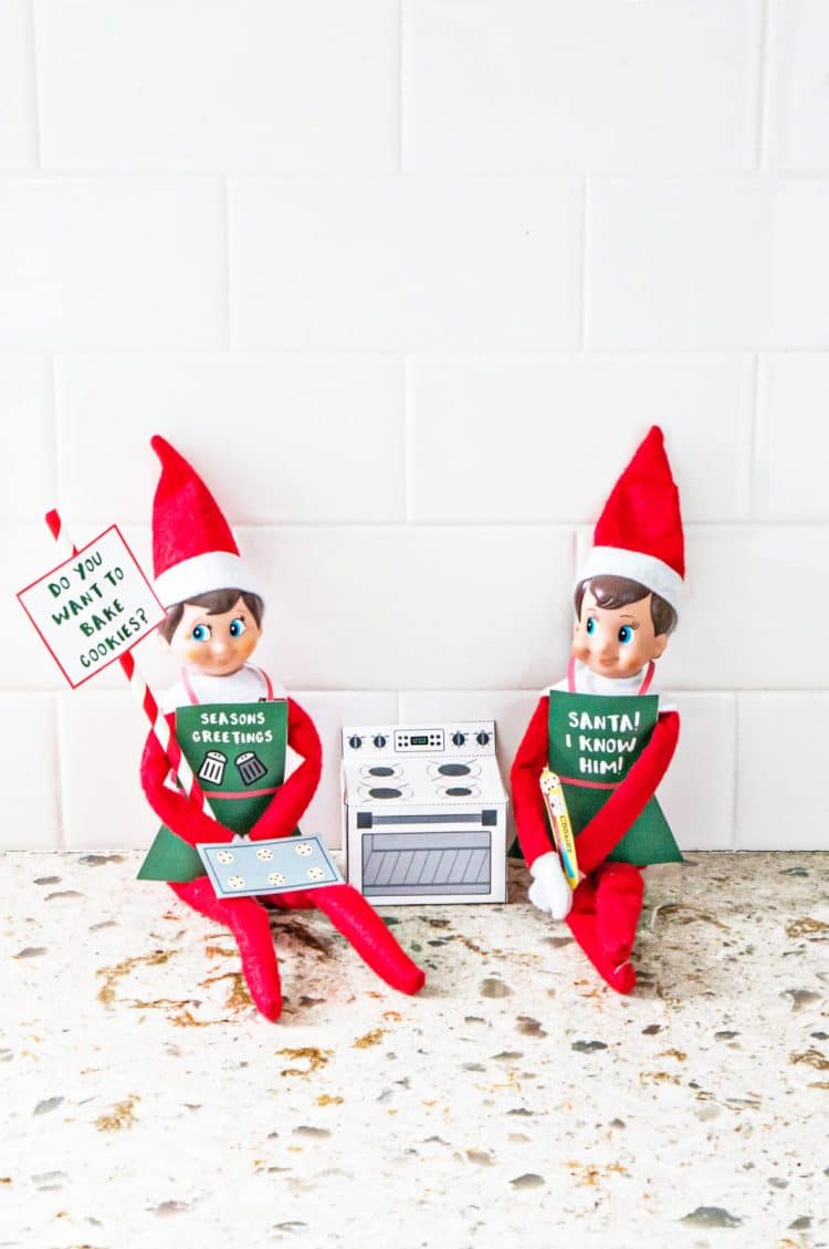 Two elves sitting with a paper oven and paper cookies prop
