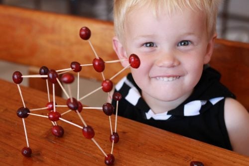 child smiling playing with cranberry engineering craft
