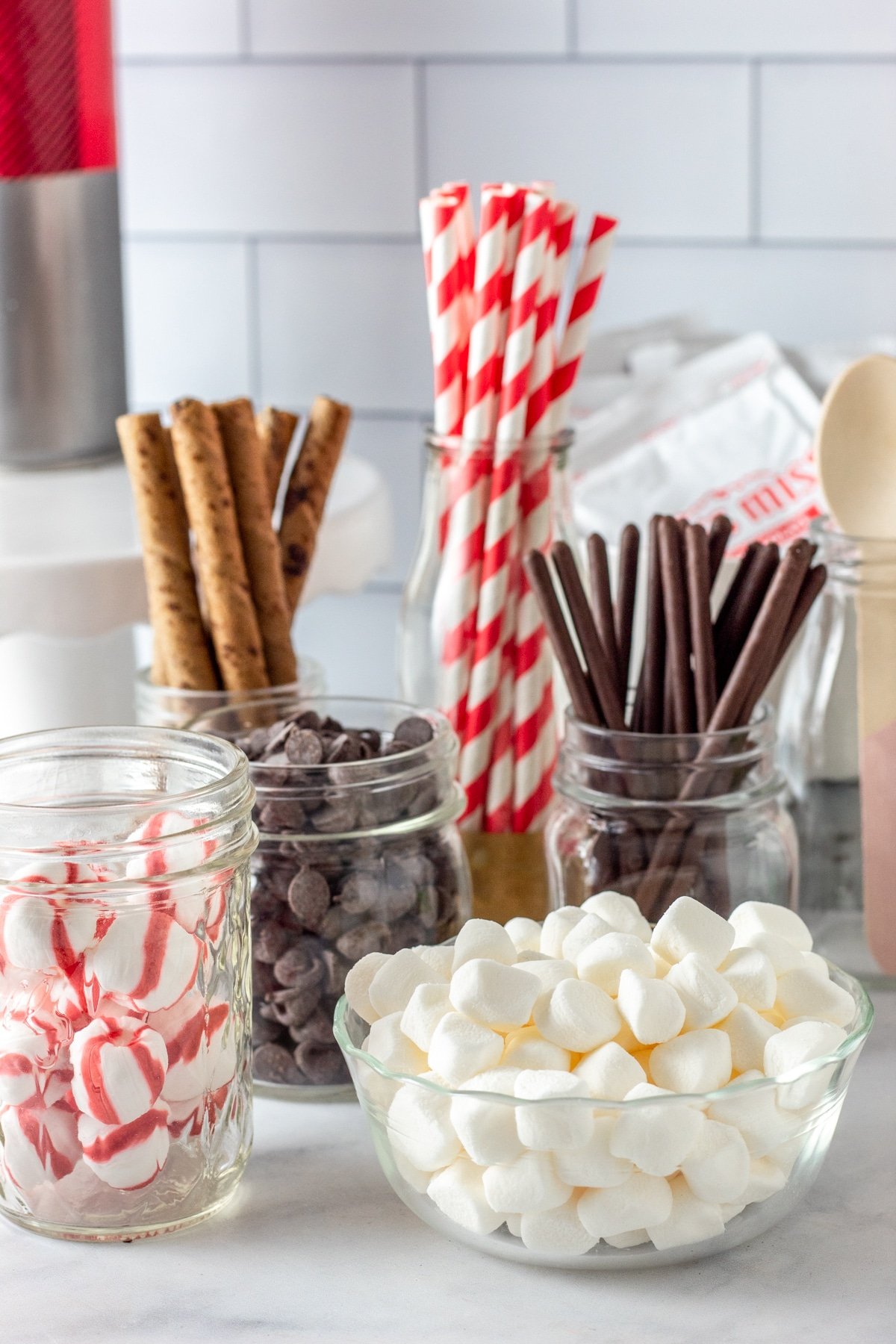 Hot cocoa bar toppings in glass bowls and jars - marshmallows, candy canes, etc. 