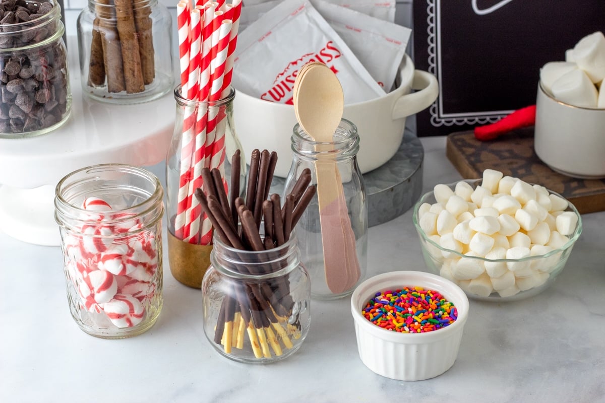 hot cocoa bar toppings in glass jars on marble kitchen counter