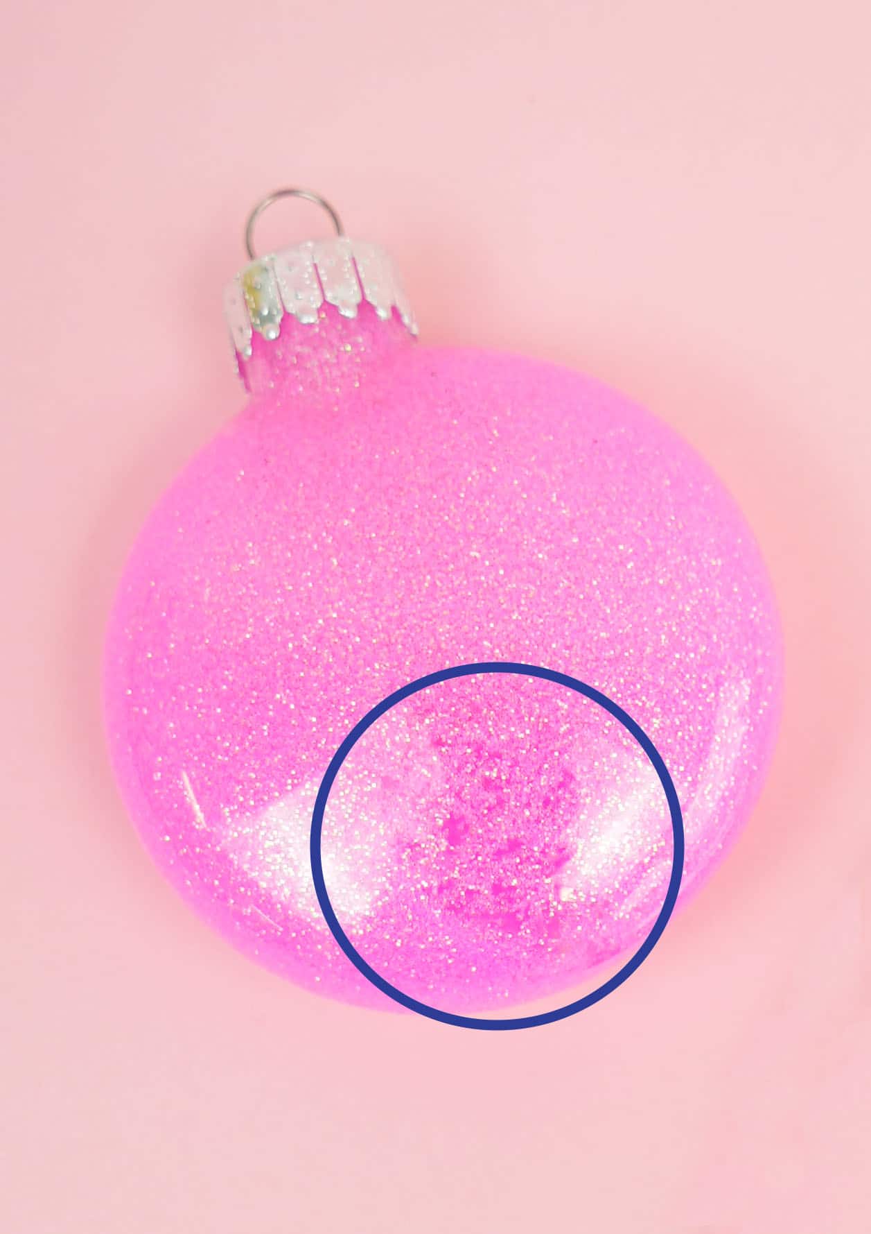 glitter ornaments are sitting on a pink surface with spot circled