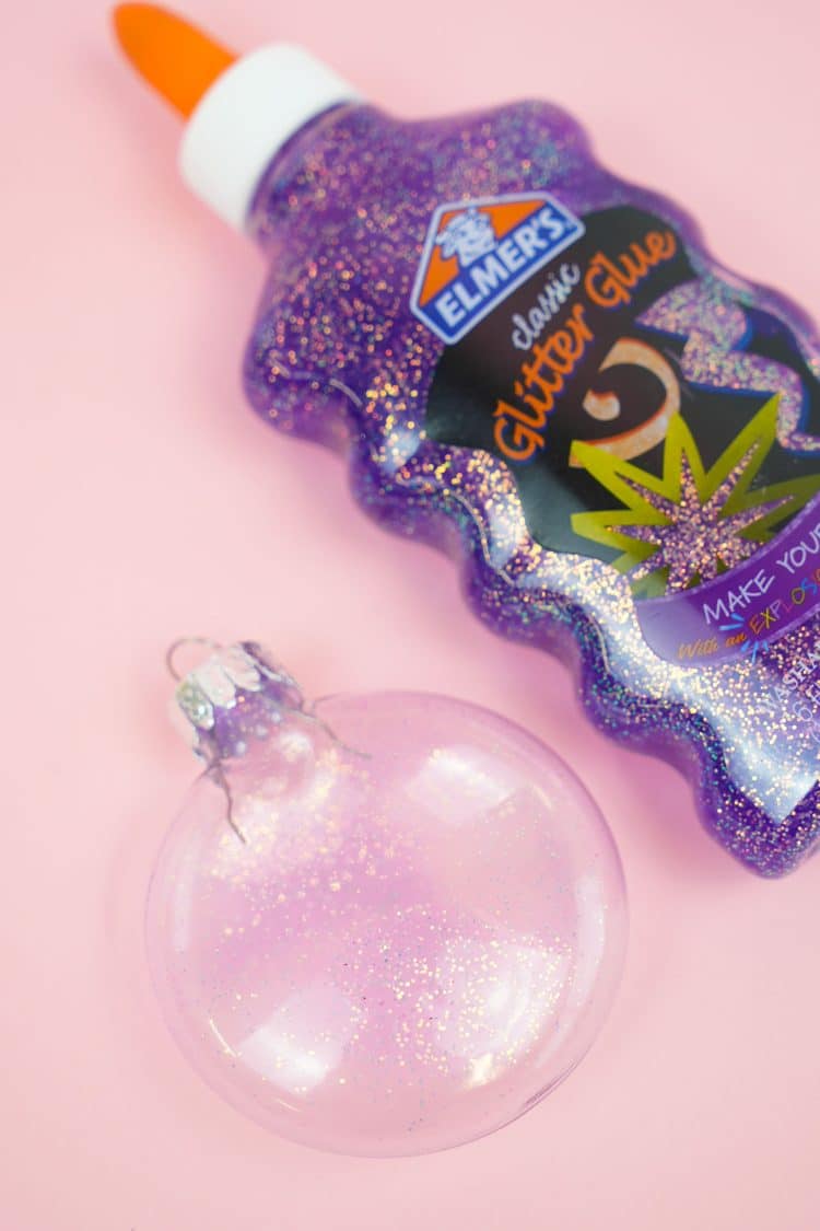 ornaments are sitting on a pink surface with glitter glue