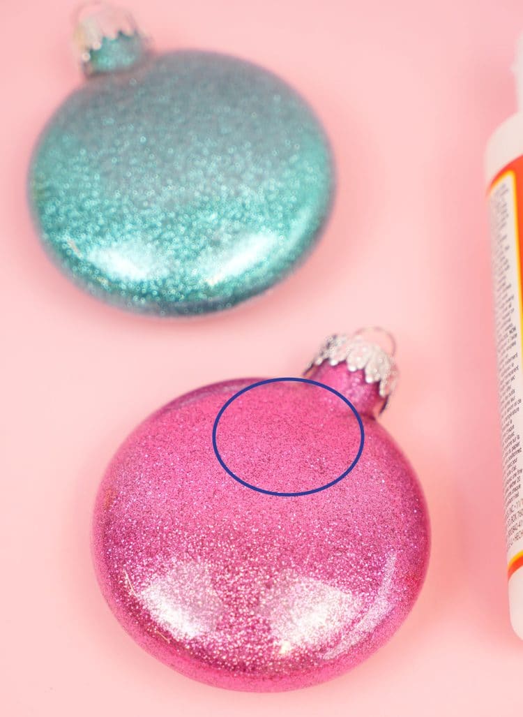 glitter ornaments are sitting on a pink surface with mod podge