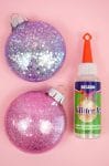 glitter ornaments are sitting on a pink surface with glitter it!