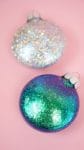 glitter ornaments are sitting on a pink surface 