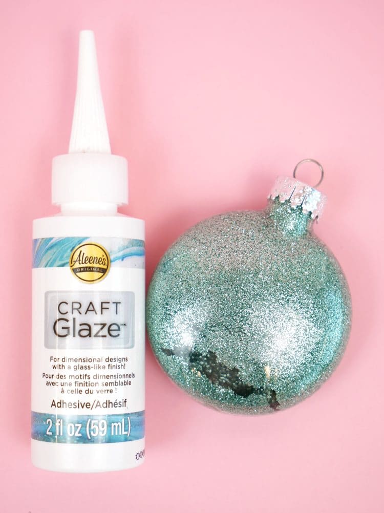 glitter ornaments are sitting on a pink surface with craft glaze