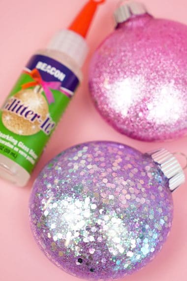 glitter ornaments are sitting on a pink surface
