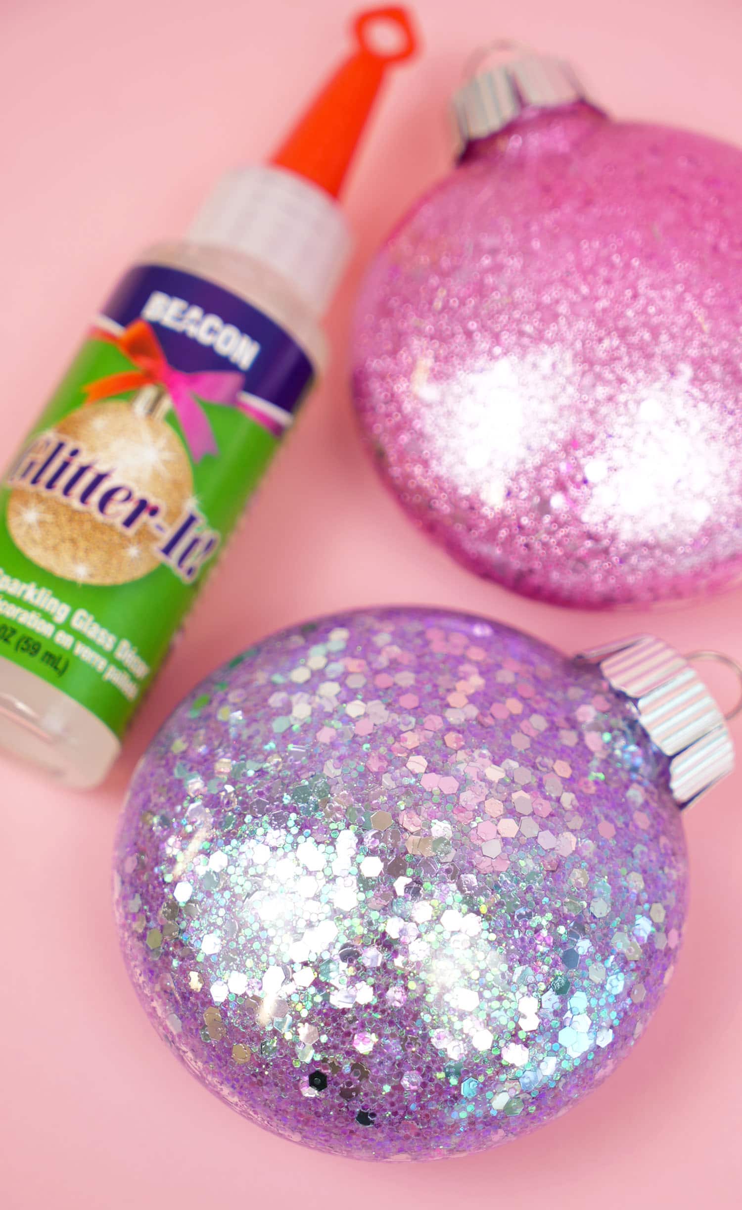 glitter ornaments are sitting on a pink surface