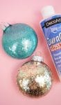 glitter ornaments are sitting on a pink surface with gloss varnish