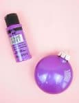 ornaments are sitting on a pink surface with purple color shift paint