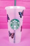 Starbucks tumbler cup with holographic butterfly SVG wrap on pink background