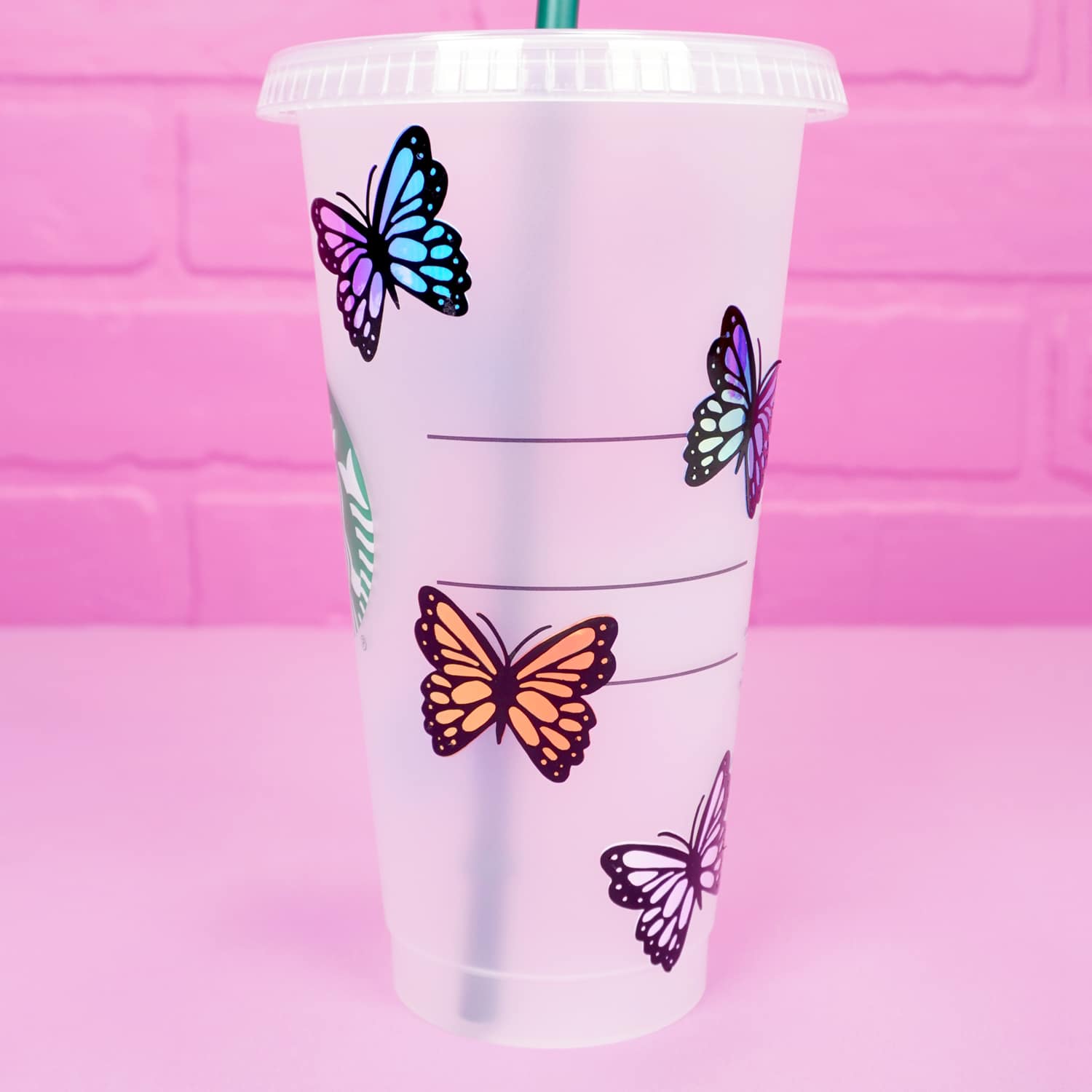 Close up of holographic butterflies on a Starbucks tumbler cup on pink background