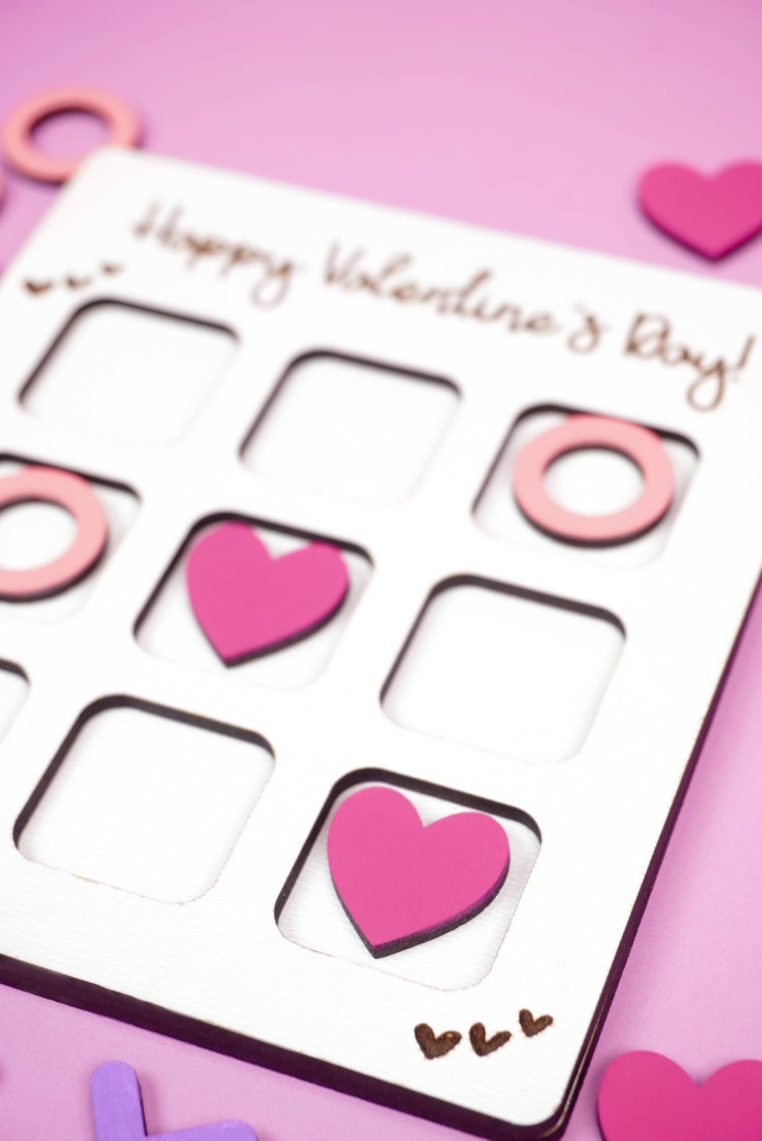 Close up of pink heart in Valentine's Day tic tac toe game on purple background