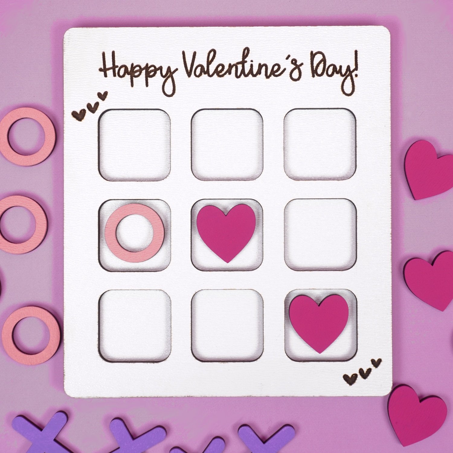 Valentine Tic Tac Toe game made with Glowforge laser SVG on a purple background with X's, O's, and pink hearts