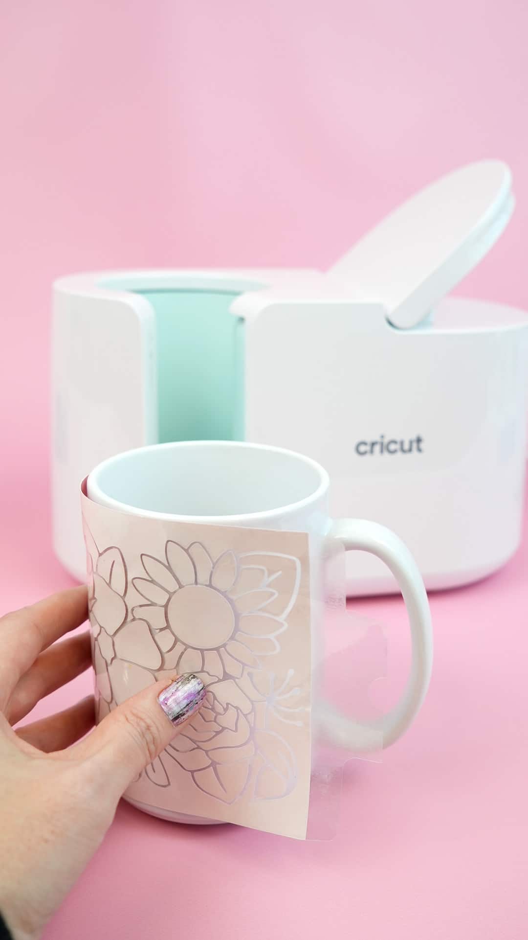 hand placing floral design on mug with cricut mug easy press