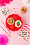 Valentine's Day sugar cookies with waffle, strawberry, and heart designs on pink background