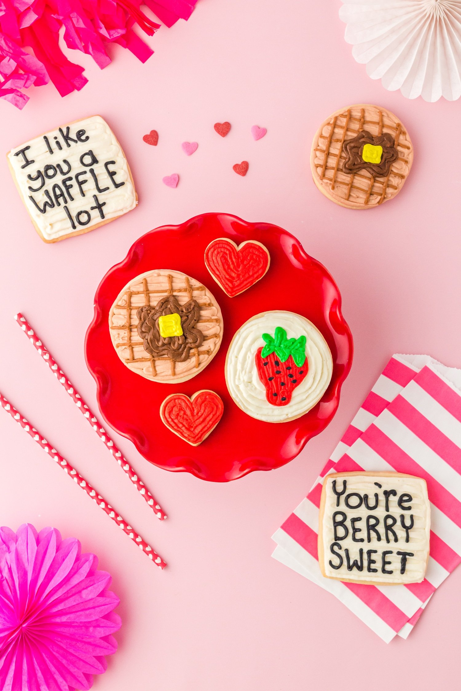 Valentine's Day sugar cookies with waffle, strawberry, and heart designs on pink background