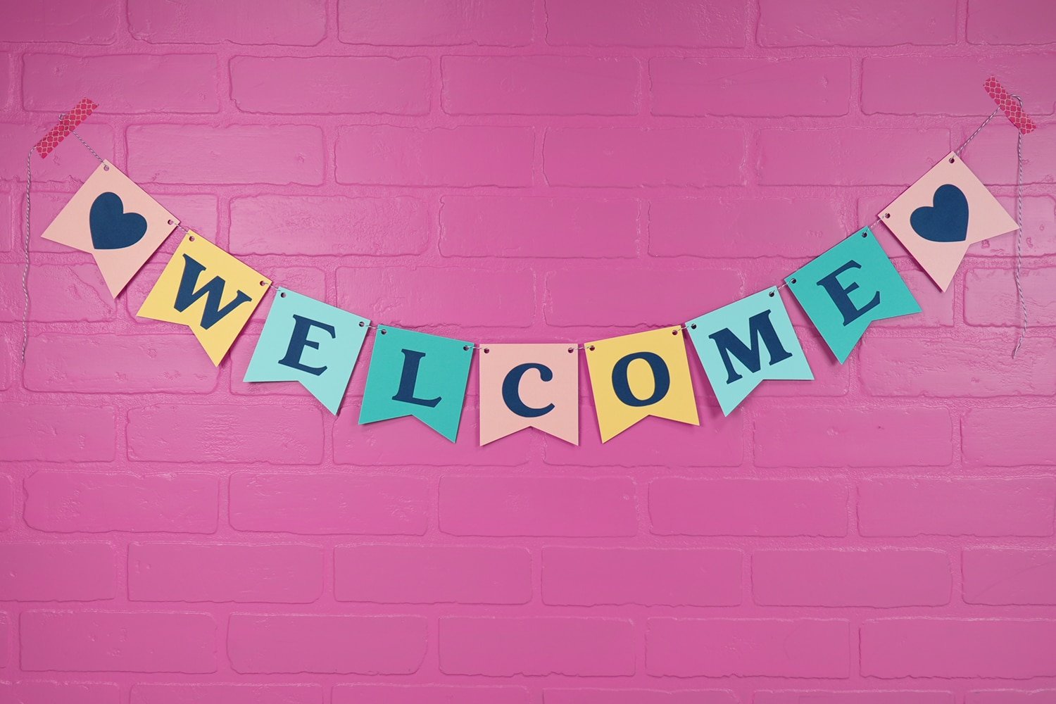 welcome banner finished against pink brick background