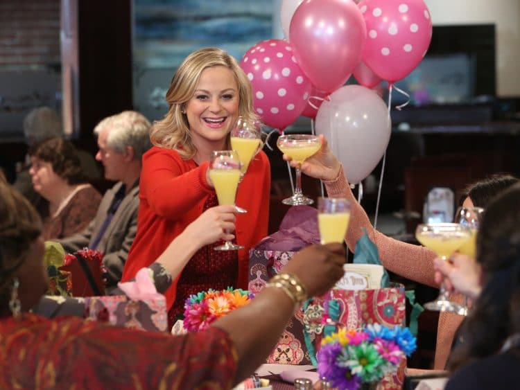 Leslie Knope from Parks and Recreation raising a mimosa toast for Galentine's Day