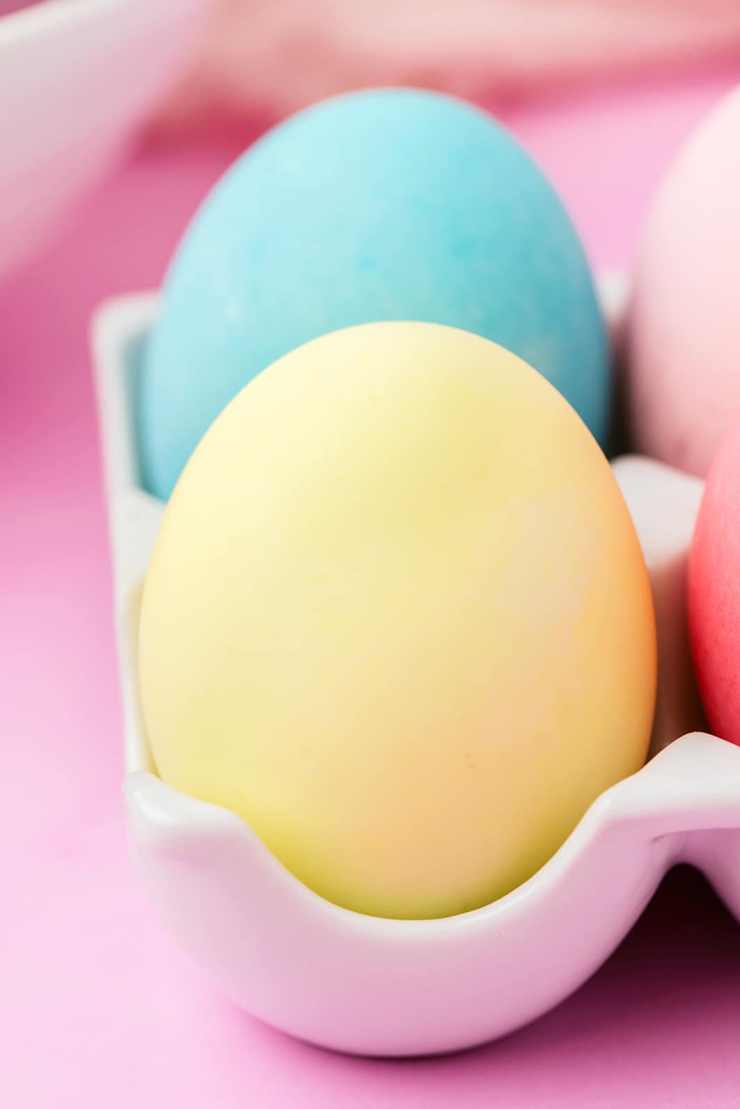 Close up of yellow food coloring dyed Easter egg with blue egg in background