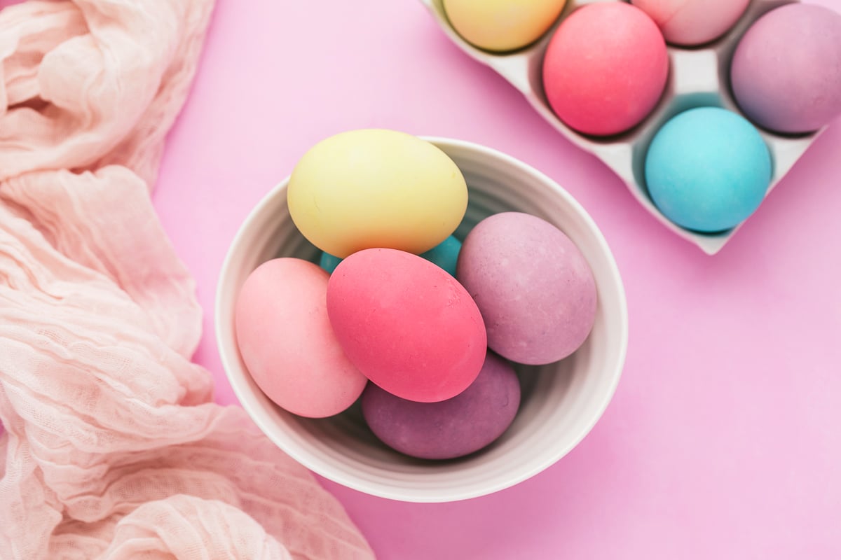 Bowl of brightly colored Easter eggs on a purple background