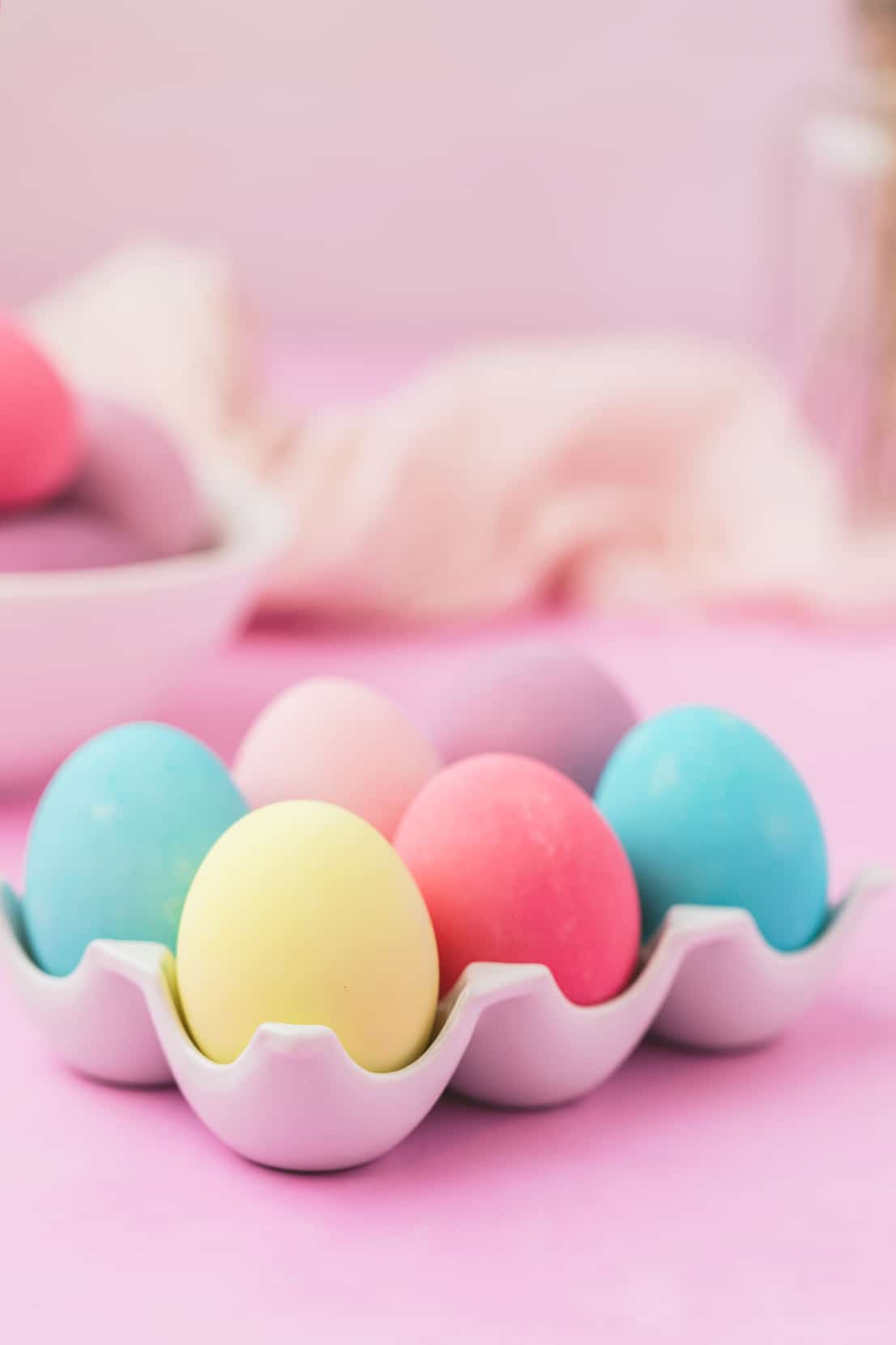 Colorful Easter eggs dyed with food coloring in an egg tray on a purple background