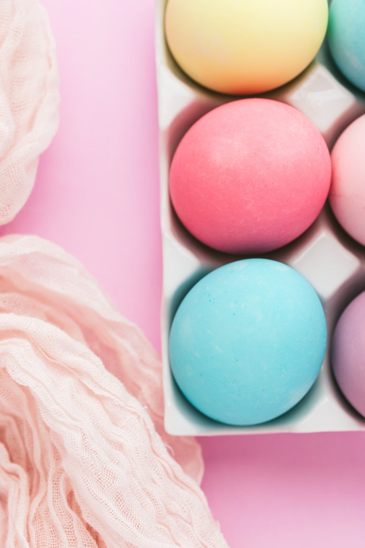 Close up shot of yellow, pink, and blue Easter eggs dyed with food coloring