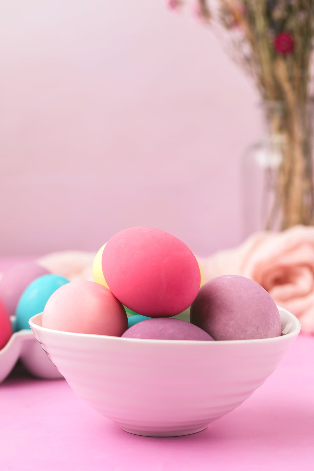 Colorful Easter eggs in a bowl on a light purple background