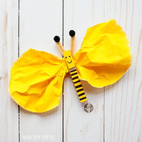 Yellow coffee filter pinched by a yellow and black striped clothespin to look like a bee.