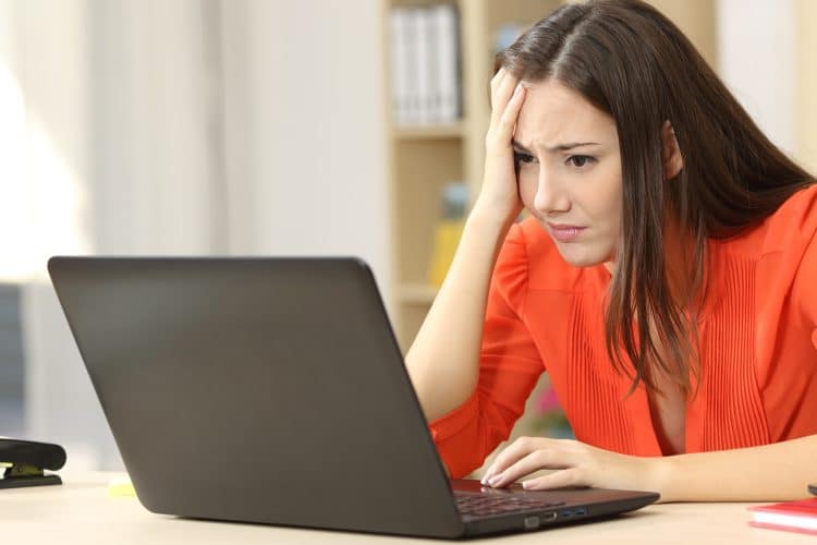 Sad and confused woman working on line with a laptop