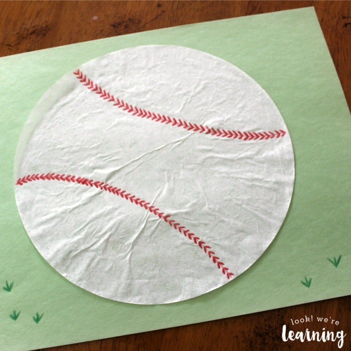 White coffee filter with red stitching to resemble a baseball on a green backgound.