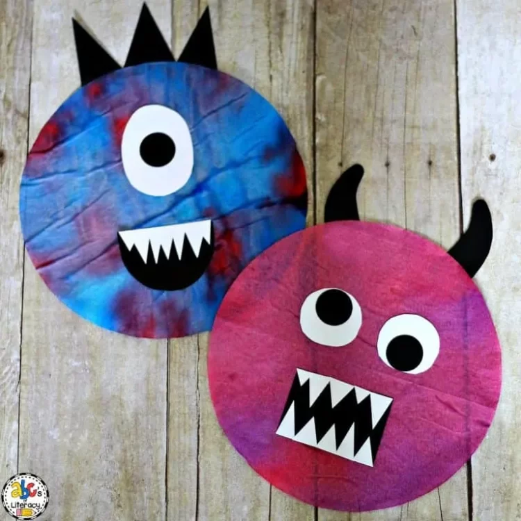 One blue and one red dyed coffee filter with paper eyes, mouth and horn to resemble monsters.