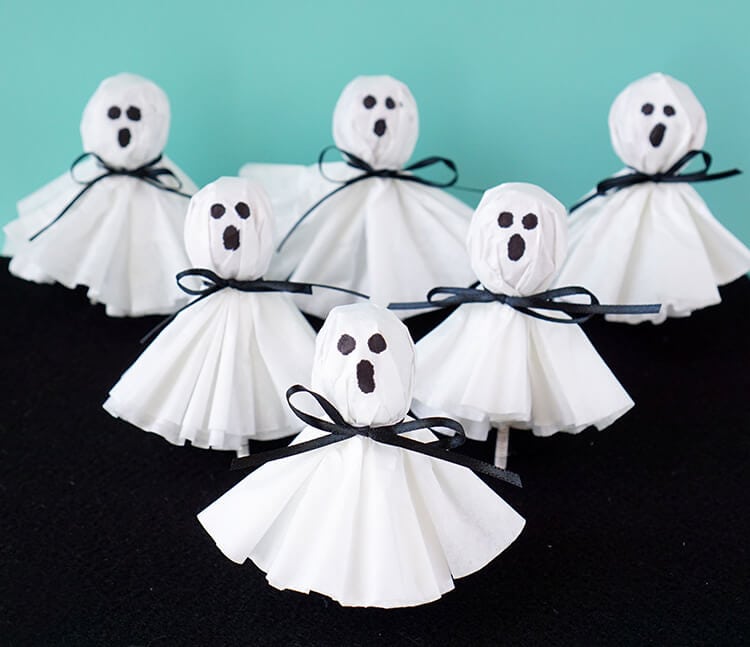 White coffee filters with black eyes over a lollipop to make ghost shapes.