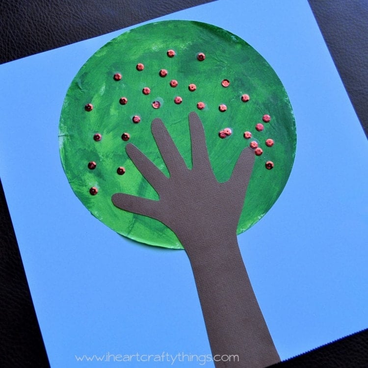 Brown handprint tree trunk with green coffee filter leaves and red sequins.