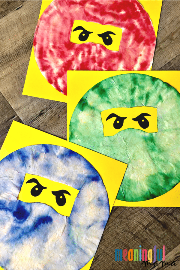 Red, green, and blue dyed coffee filter on yellow background made to look like Lego Ninjago characters.