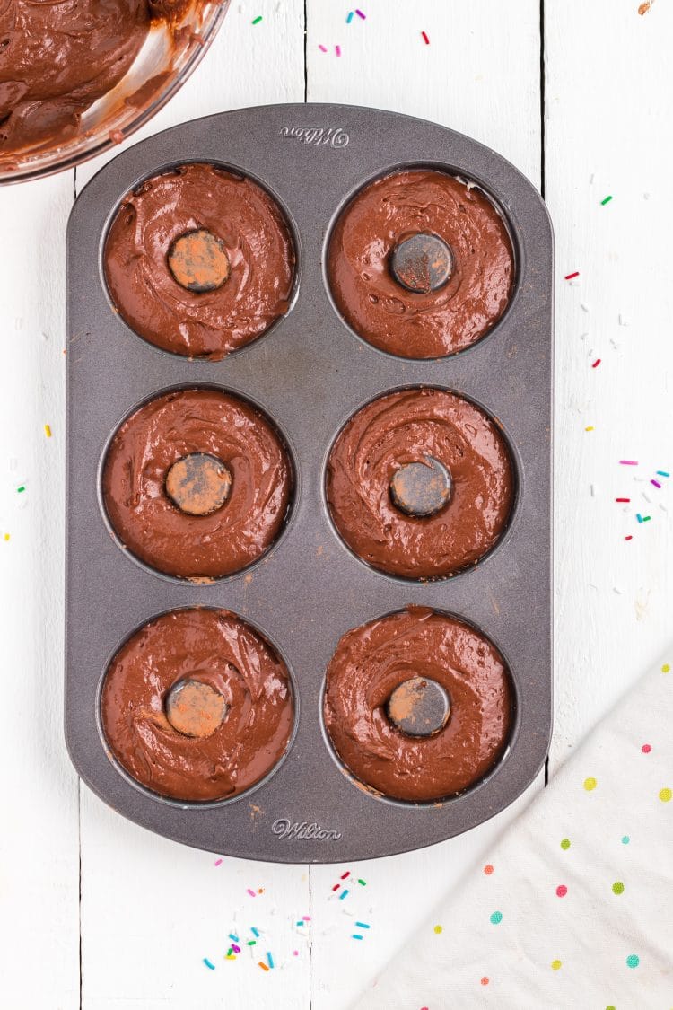 freshly piped chocolate donut batter in donut pan before baking