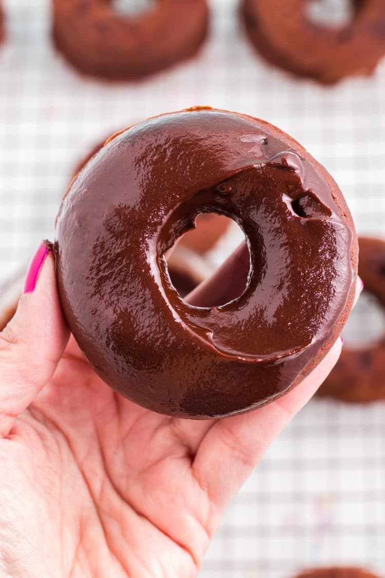 Fresh dipped iced chocolate donut in hand